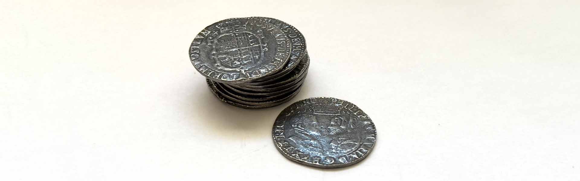 A stack of 1555 Tudor shillings, including one displaying the crowned profiles of Philip and Mary, symbolizing the religious turmoil and royal power struggles that shaped the adventures of Francis Drake. This is an announcement from the author of the historical fiction novel Sic Parvis Magna.